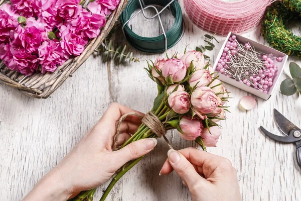Frau macht Strauß aus rosa Rosen. — Stockfoto