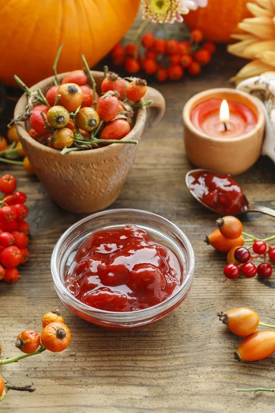 Bowl of jam and pot of rose hip. Flowers and pumpkins — Stock Photo, Image