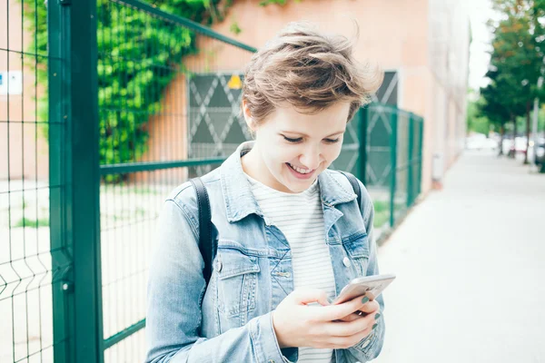 Счастливая смеющаяся женщина со смартфоном на улице — стоковое фото