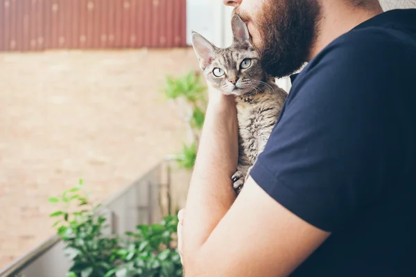 一个留着胡子的男人拥抱着他可爱的德文郡 rex 猫 — 图库照片