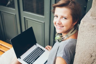 Temiz havada sokak kafede otururken dizüstü bilgisayar ile güzel bir beyaz kadın Blogger portre rahat