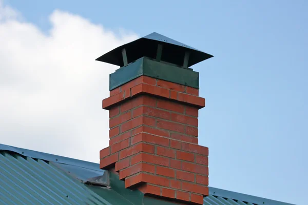 Chimenea de ladrillo en el techo de metal verde —  Fotos de Stock