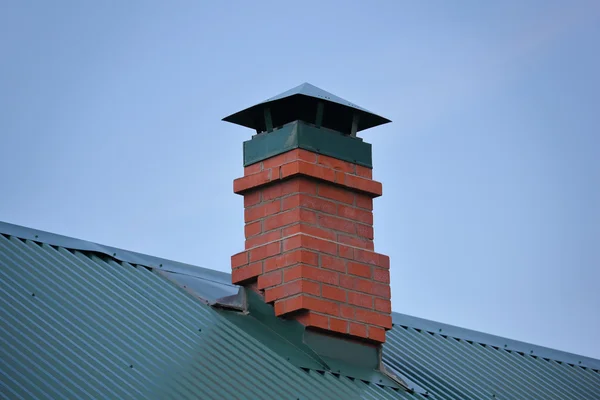 Brick chimney on the green metal roof — Stock Photo, Image