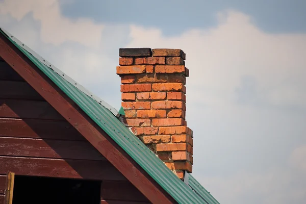 Brick chimney on the green metal roof — Stock Photo, Image