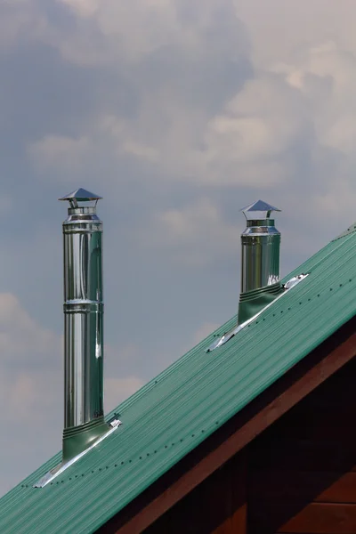 Металлическая выхлопная труба на зеленой металлической крыше — стоковое фото