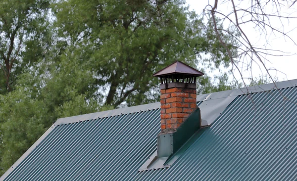 Кирпичный дымоход на зеленой металлической крыше Лицензионные Стоковые Фото