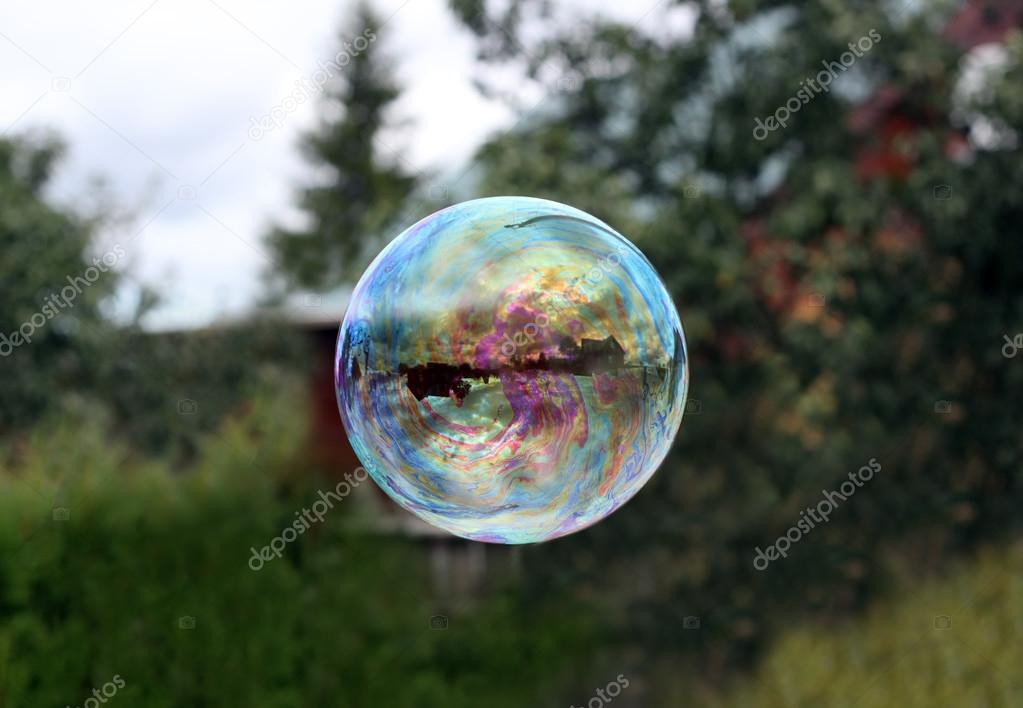Flying soap bubble reflecting village house