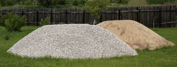 Heaps of sand and broken stone on the grass — Stock Photo, Image