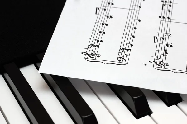 Arkusz papieru muzyka leżącego na klawiszach fortepianu th — Zdjęcie stockowe