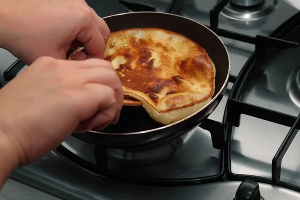 Two woman hands turning pancake by wooden trowel — Stock Photo, Image