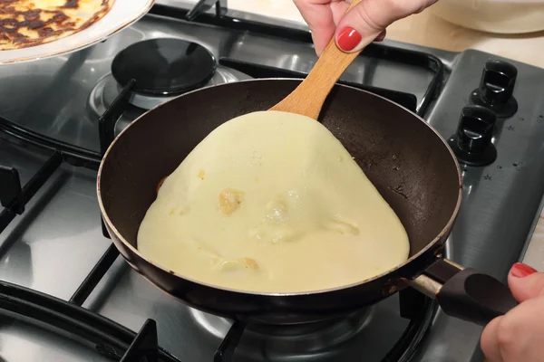 Woman's hands turning pancake by wooden trowel — Stock Photo, Image