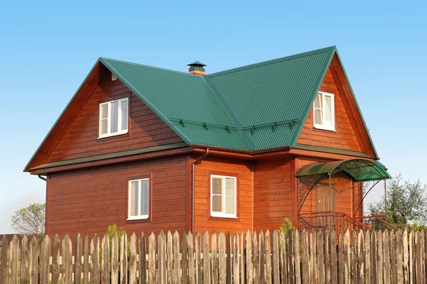 Wooden house under green metal roof with white plastic windows with jalousie — Stock Photo, Image