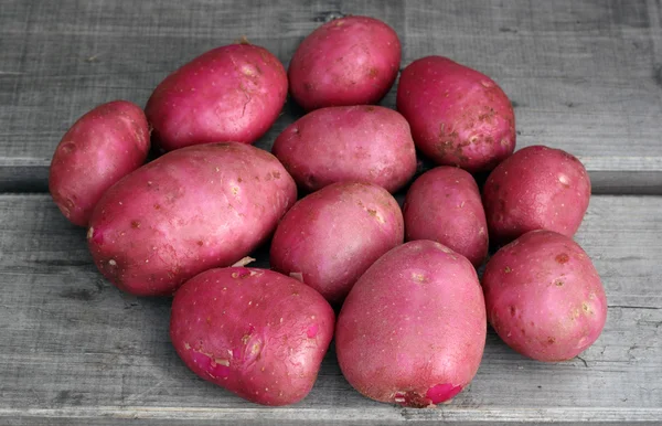 New red potetoes on the old board surface — Stock Photo, Image