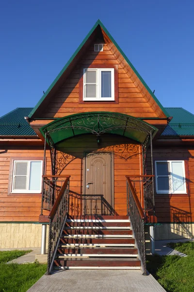 Drewniany dom z widokiem na schodkach zielony dach metalowy — Zdjęcie stockowe