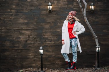 Beyaz takım elbiseli ve kırmızılı kadın ahşap arka planda ışığa yakın durun.