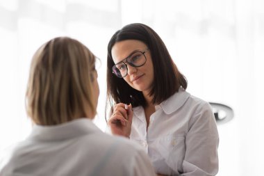 Beyazlar içindeki beuty ustası ve siyah saçlı aydınlık oda prosedürü uygulayacak.
