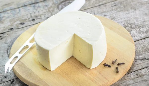 Queijo branco em uma bandeja de madeira . — Fotografia de Stock