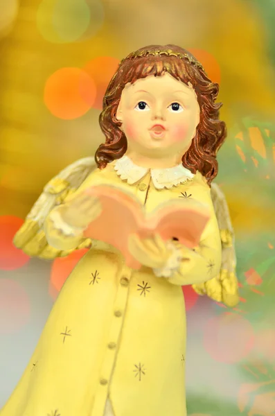 Christmas decoration, figure of little angel singing carols against bokeh background — Stock Photo, Image