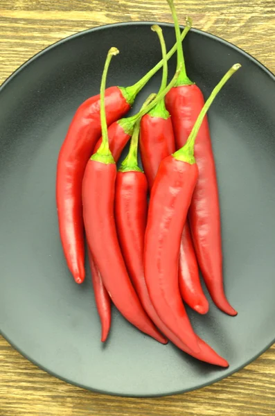 Pimientos rojos picantes en plato negro —  Fotos de Stock