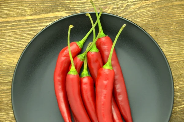 Pimientos rojos picantes en plato negro —  Fotos de Stock