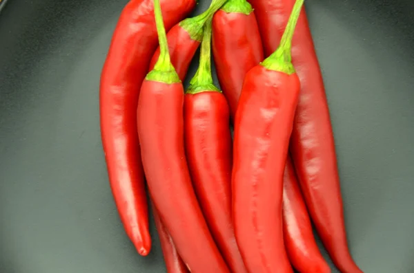 Pimientos rojos picantes en plato negro — Foto de Stock