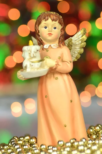 Christmas decoration, figure of angel holding a candle against bokeh background — Stock Photo, Image