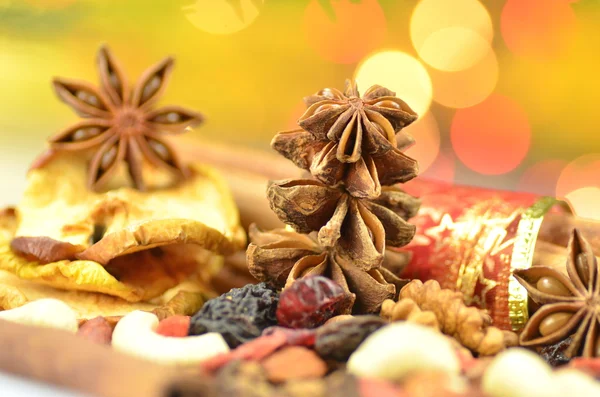 Christmas spices, nuts, cookies and dried fruits on bokeh background — Stock Photo, Image