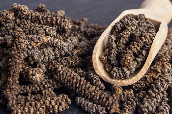 Houten lepel met lange peper op donkere stenen achtergrond — Stockfoto