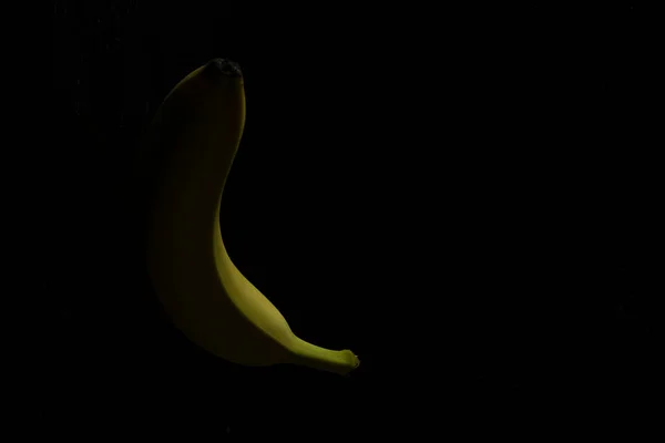 Banana amarela única em fundo de madeira preta — Fotografia de Stock