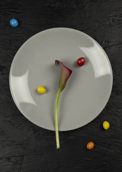 Chocolate yellow candy and flower calla on the gray plate