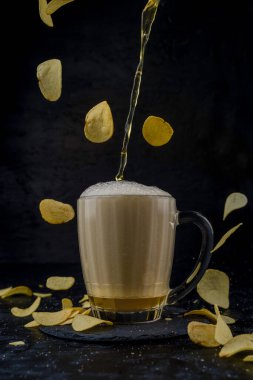 Siyah arka planda uçan patates cipsli bira.