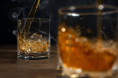 Viski tahtada buz küpleriyle içer ve su sıçratır..