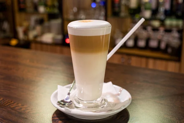 Café con leche en taza de vidrio sobre mesa de madera en bar —  Fotos de Stock