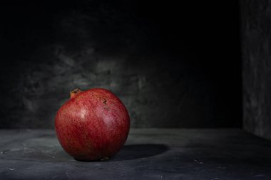 Siyah arka planda taze, olgun bir nar. Kırmızı bir meyvenin yakın çekimi.