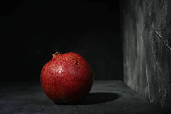 Frischer reifer Granatapfel auf schwarzem Hintergrund. Nahaufnahme einer roten Frucht. — Stockfoto
