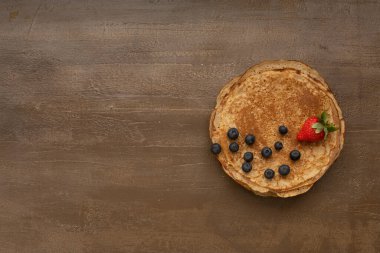 Ahşap masada böğürtlenli ev yapımı kırsal krep. Masa üstü görünümü. Maslenitsa yemeği.