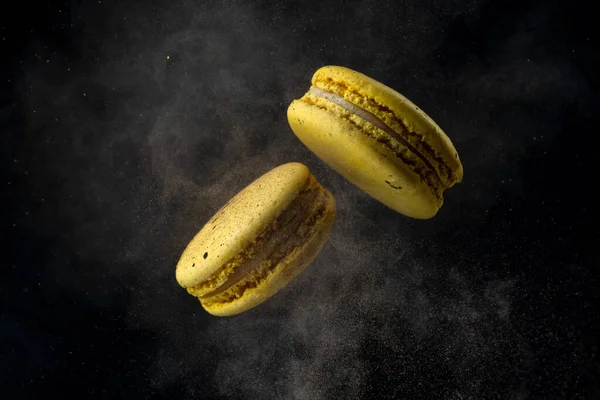 Fliegende Makronen auf schwarzem Hintergrund, die mit Kakao in Bewegung gefrieren. Stockbild