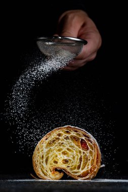 Koyu ahşap arka planda kruvasan ve pudra kaplı kruvasan pişir..