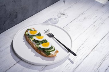 Kızarmış ekmekli tost. Sarı sarısı ve beyaz tabakta bitkilerle kaynamış yumurta.