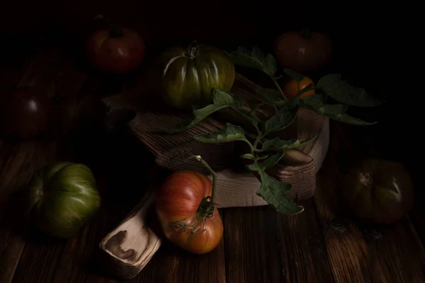 Κόκκινες ραβδωτές ντομάτες σε ένα όμορφο ξύλινο ξύλο κοπής σε ξύλινο φόντο. Χαμηλή φωτογραφία κλειδιού. — Φωτογραφία Αρχείου
