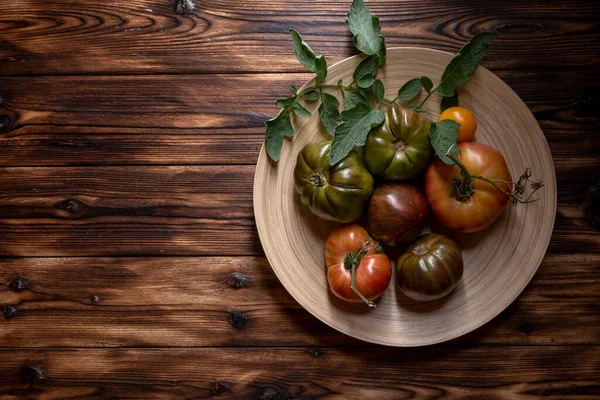 暗い木製の背景に木製のプレートに新鮮なトマト。トマトの収穫。鍵が低い. — ストック写真
