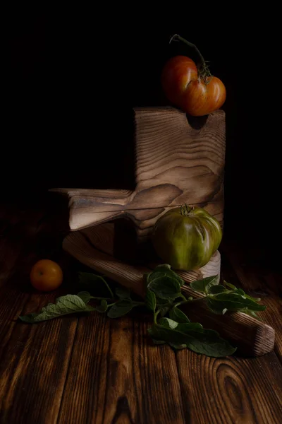 Κόκκινες ραβδωτές ντομάτες σε ένα όμορφο ξύλινο ξύλο κοπής σε ξύλινο φόντο. Χαμηλή φωτογραφία κλειδιού. — Φωτογραφία Αρχείου