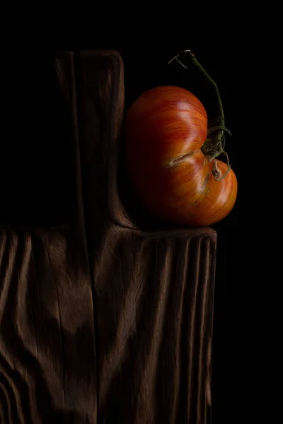 Altura de legumes frescos maduros tomates coloridos e tábua de madeira sobre mesa de madeira velha. Atmosfera rústica escura. tecla baixa. — Fotografia de Stock