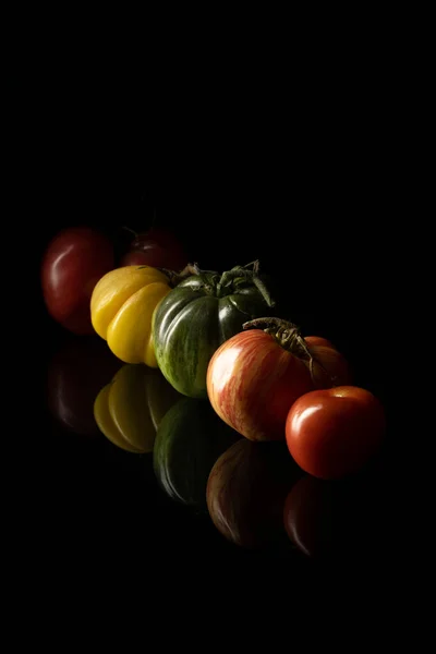 Διαφορετικές φρέσκες ντομάτες σε μαύρο τραπέζι — Φωτογραφία Αρχείου