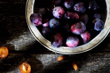 Tahta arka planda demir kasede erik var.