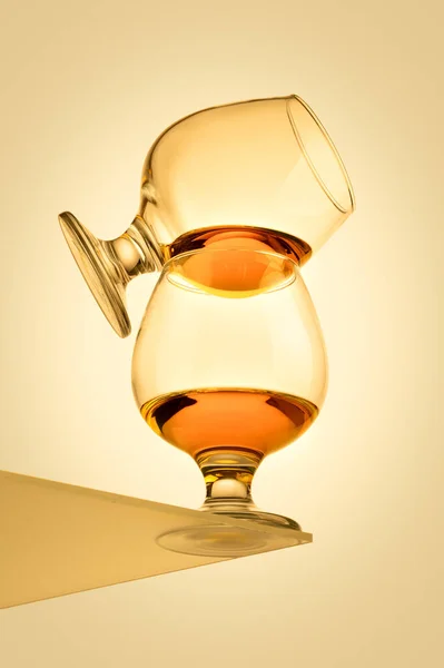 Twee glazen cognac op elkaar gestapeld over een gele achtergrond — Stockfoto