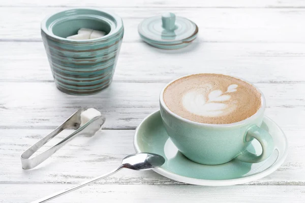 Xícara de café cappuccino em uma caneca azul no fundo de madeira branco — Fotografia de Stock