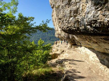 Sonbahar Parkı 'nda güneşli bir günde bir kayanın altındaki bir dağ yolunda turist rotası..