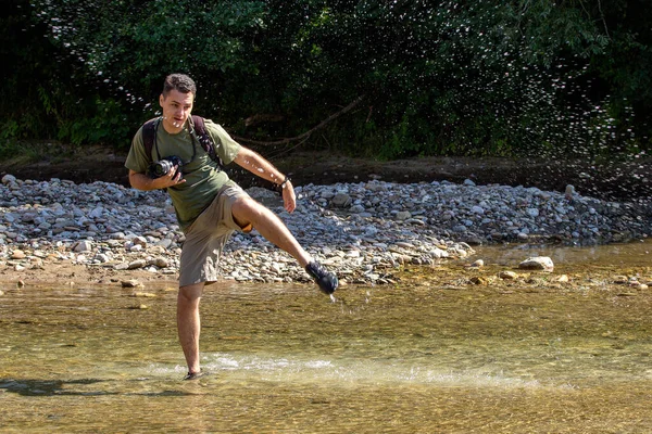 Güneşli bir günde, bir dağ nehrinde, suda dans eden genç bir adam..