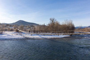 Dağ eteklerinde kış, buzsuz bir nehir, dondurucu bir sabah, yükselen güneşin ışınlarında..